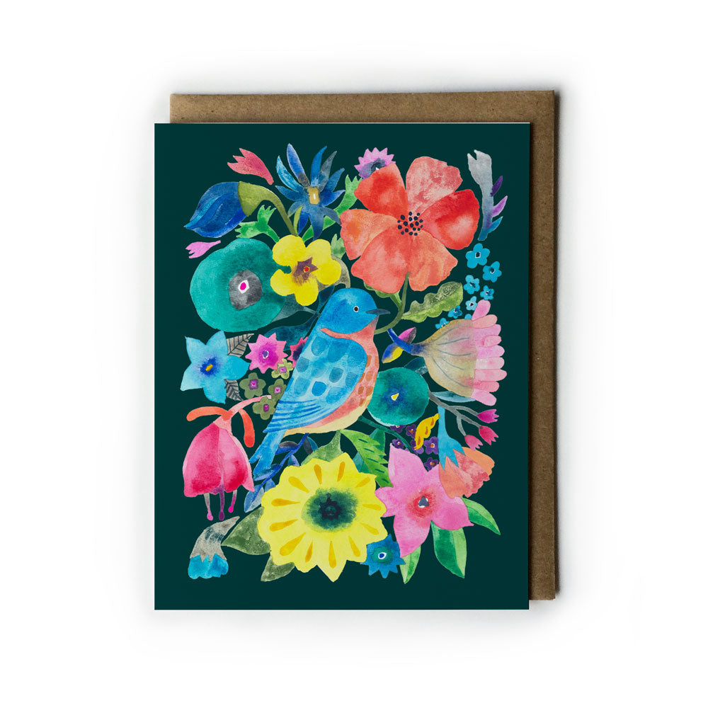 Colorful greeting card featuring vibrant watercolor illustration of bluebird perched among diverse flowers on dark green background, accompanied by kraft envelope