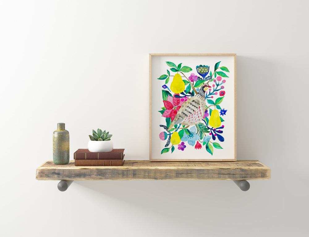Colorful giclee art print of partridge and pears surrounded by vibrant flowers and leaves, displayed on rustic wooden shelf with decorative items, showcasing Partridge and Pear artwork in a home setting