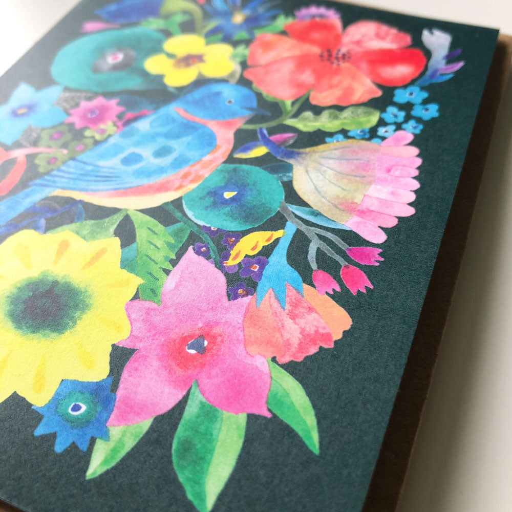Vibrant watercolor greeting card featuring a blue bird surrounded by colorful flowers on a dark background, showcasing a beautiful floral design perfect for various occasions