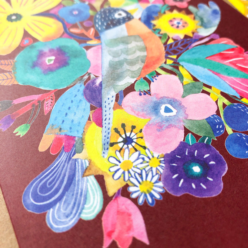 Colorful watercolor illustration of a stylized robin surrounded by vibrant flowers on a greeting card, featuring a mix of floral shapes and patterns in various bright hues against a burgundy background