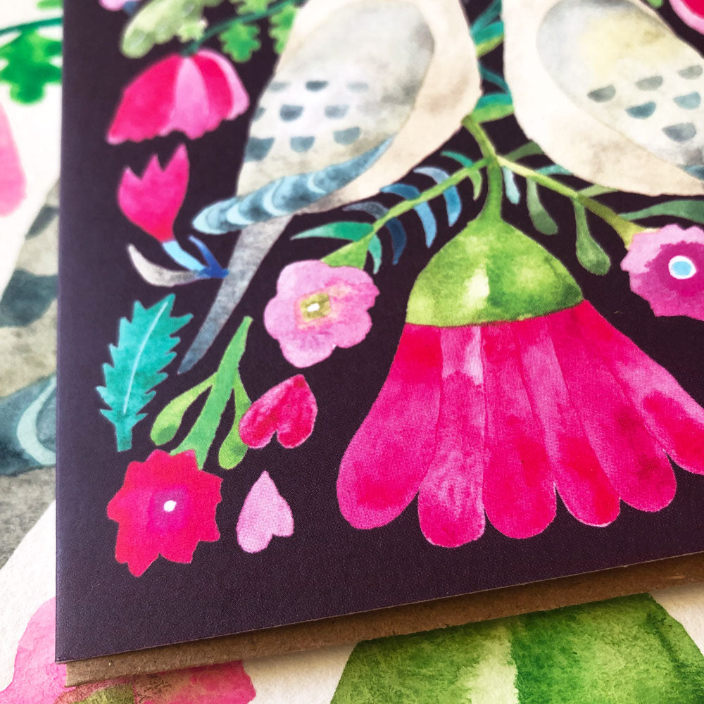 Colorful watercolor greeting card featuring mourning doves, vibrant pink flowers, and green leaves on a black background, showcasing a romantic and nature-inspired design perfect for special occasions.