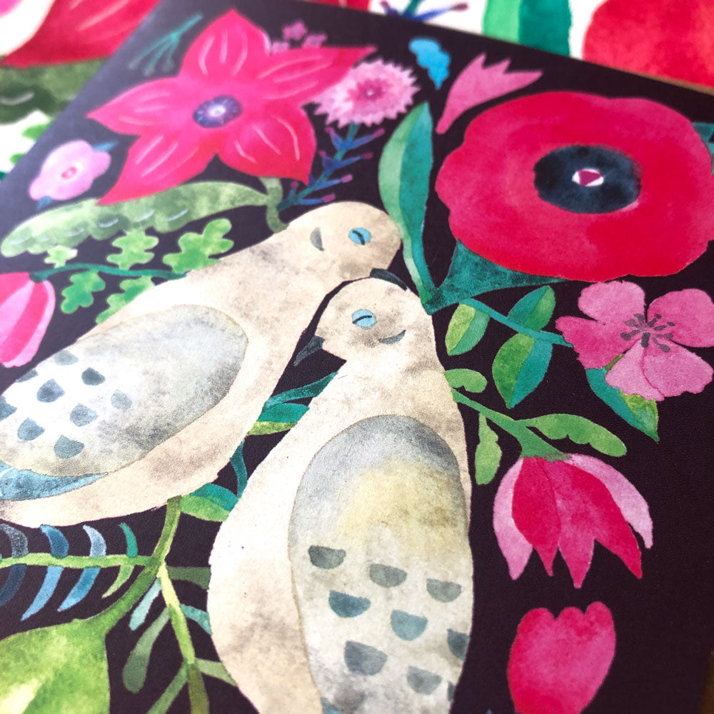 Colorful watercolor greeting card featuring two mourning doves surrounded by vibrant flowers including poppies, tulips, and daisies on a dark background, perfect for expressing love and affection