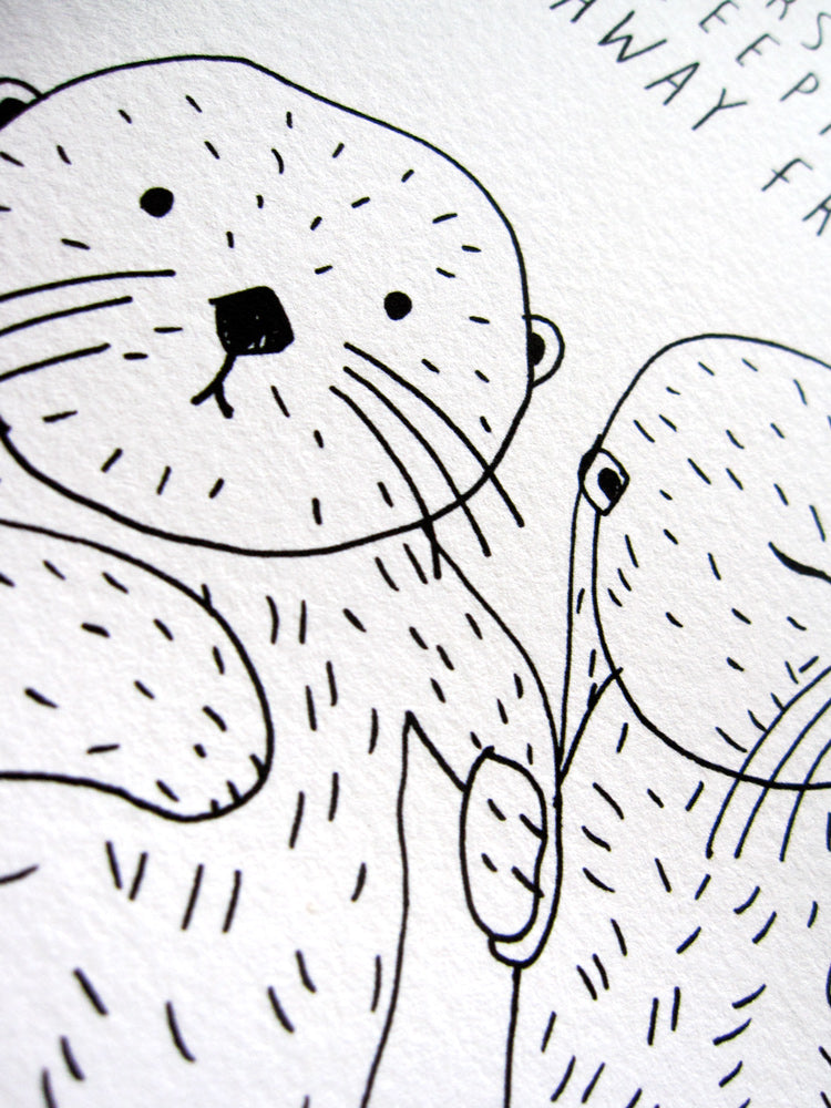 Close-up of a hand-drawn pen and ink illustration featuring two sea otters holding hands. The otters are depicted with simple, expressive lines, showcasing their round bodies, whiskers, and adorable facial features. The image captures the charming and endearing nature of sea otters' behavior.