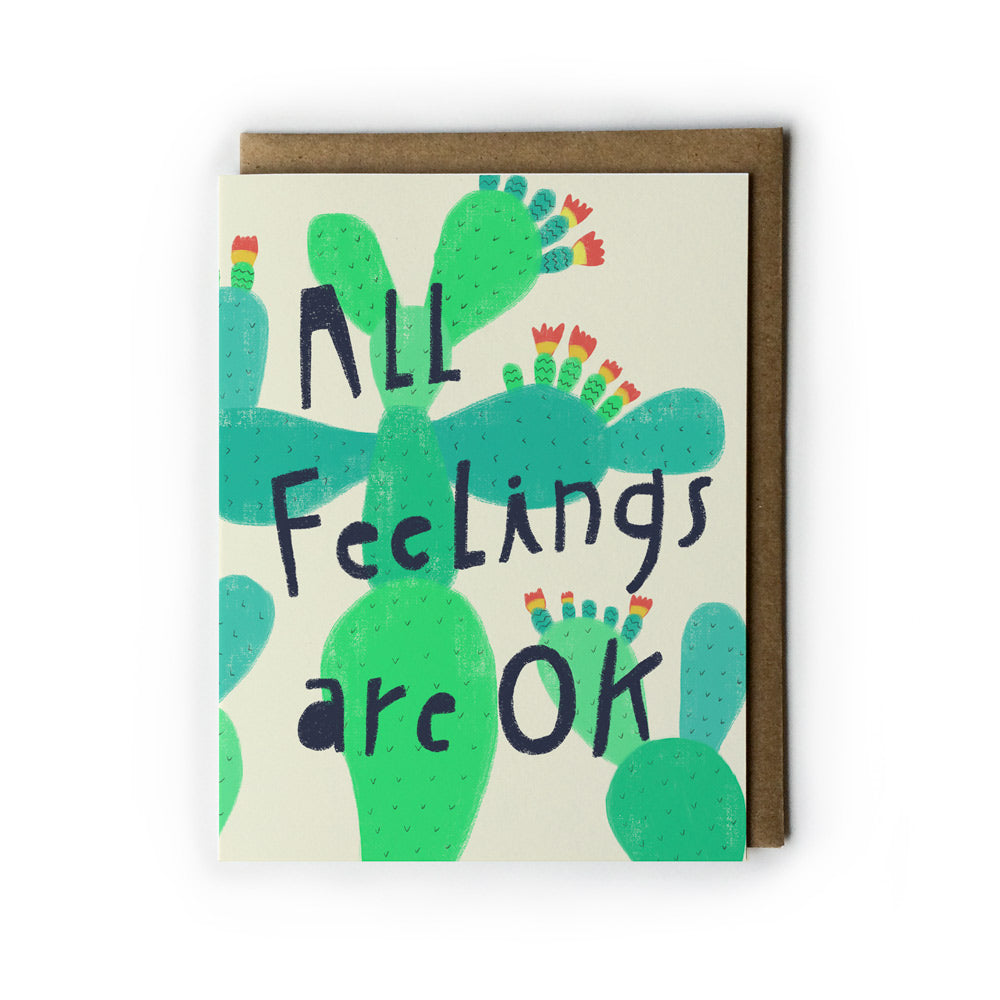 Greeting card with hand-drawn green cactus design and text "All Feelings are OK" on cream background, paired with brown kraft paper envelope