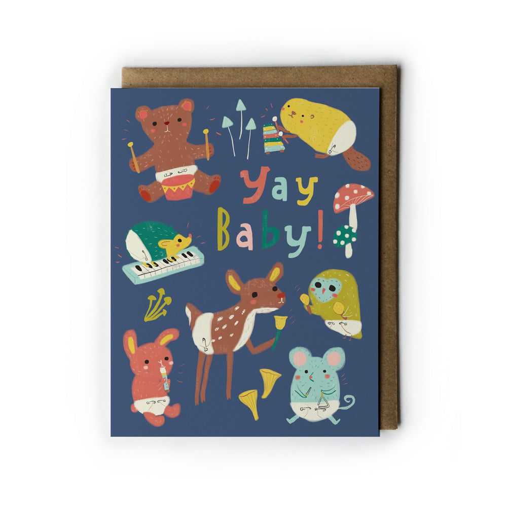 Colorful greeting card featuring cute baby woodland animals in diapers playing instruments, with "Yay Baby!" text, on navy background with kraft envelope