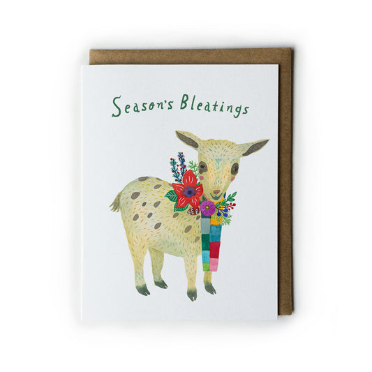 Holiday greeting card featuring a watercolor illustration of a spotted baby goat wearing a colorful scarf with flowers. Text reads "Season's Bleatings" in green. White card with brown kraft envelope.