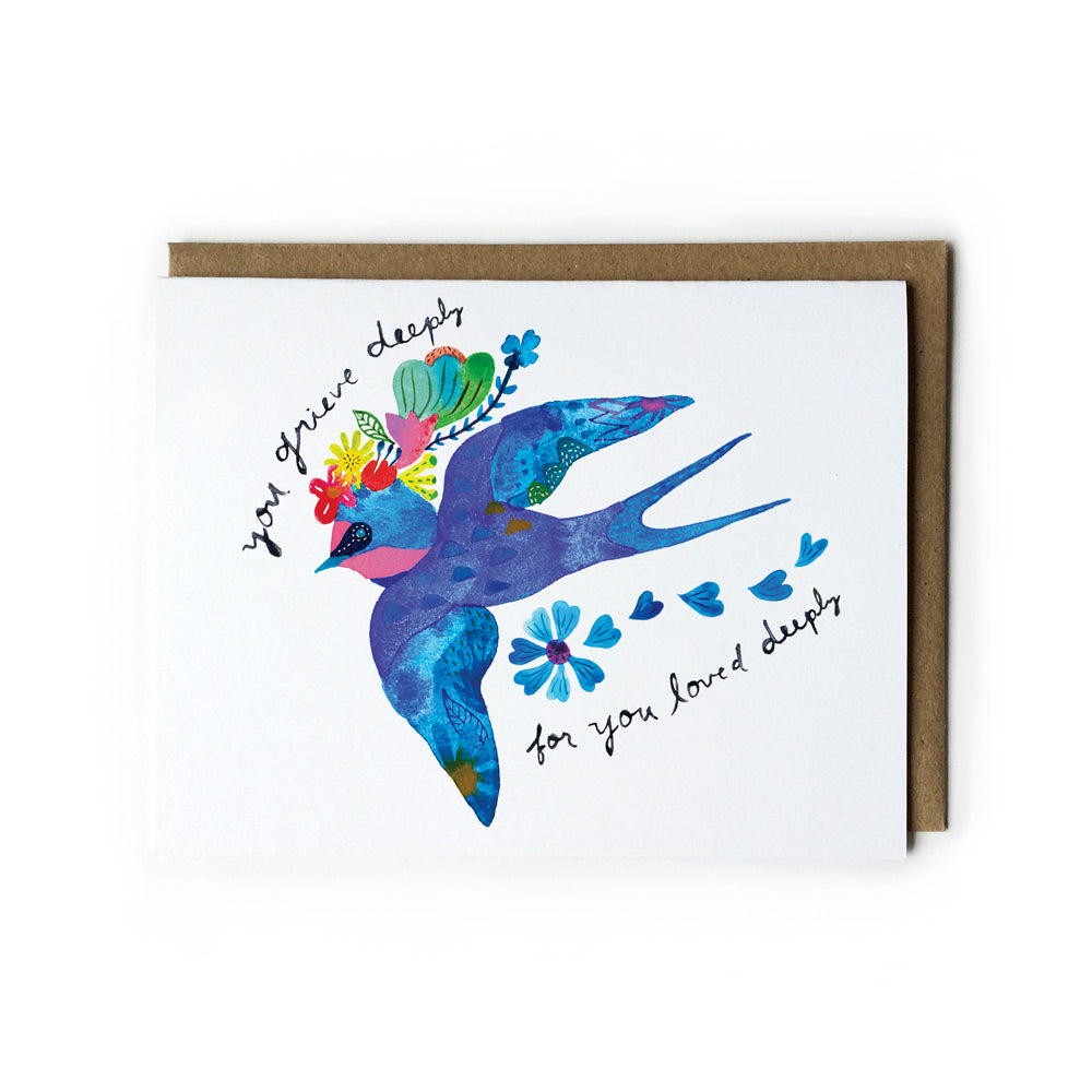 Watercolor sympathy card featuring a vibrant blue swallow in flight, adorned with colorful flowers and text reading "your grace sleeps for you loved deeply", paired with a kraft paper envelope