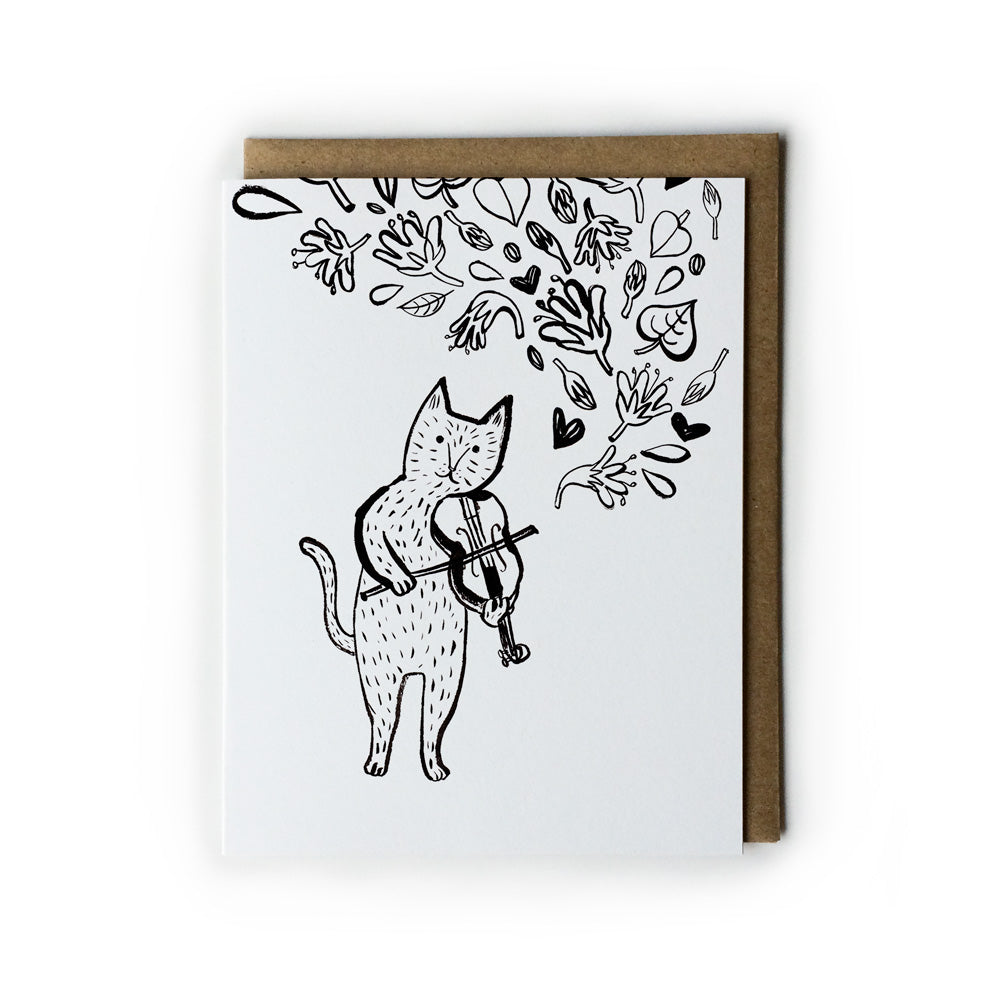 Black and white greeting card featuring a whimsical illustration of a cat playing violin, surrounded by floating floral elements and hearts. Paired with a kraft envelope.