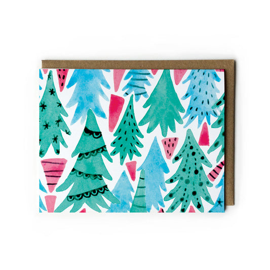 Whimsical watercolor Christmas forest greeting card featuring stylized green, blue, and pink trees with decorative patterns, stars, and triangular shapes on white background, paired with kraft paper envelope