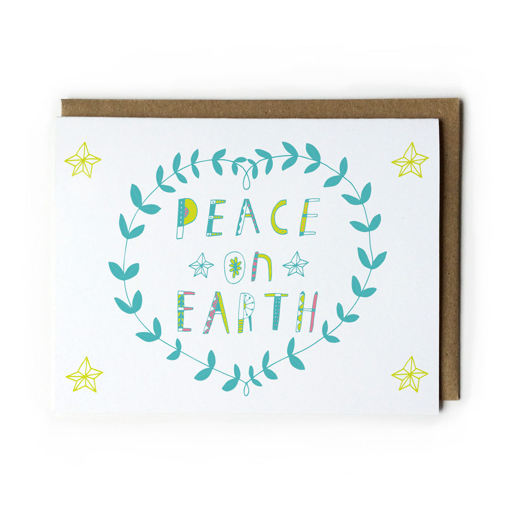 Holiday greeting card featuring hand-lettered "Peace on Earth" text in colorful teal and yellow, surrounded by a wreath-like leaf design and yellow stars, paired with a kraft paper envelope
