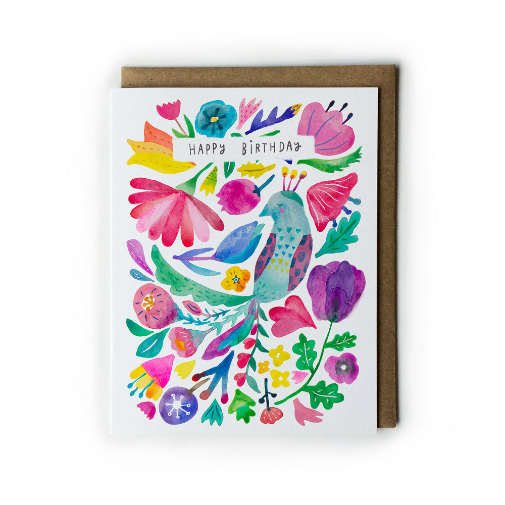 Vibrant watercolor birthday card featuring colorful floral design with stylized peacock, various flowers, and leaves. Text reads "Happy Birthday" in center. Accompanied by kraft paper envelope.