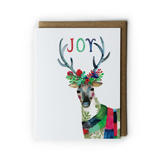 Colorful watercolor holiday card featuring a festive reindeer with floral antlers, wearing a patchwork scarf, and the word 'JOY' spelled out above its head, accompanied by a kraft paper envelope