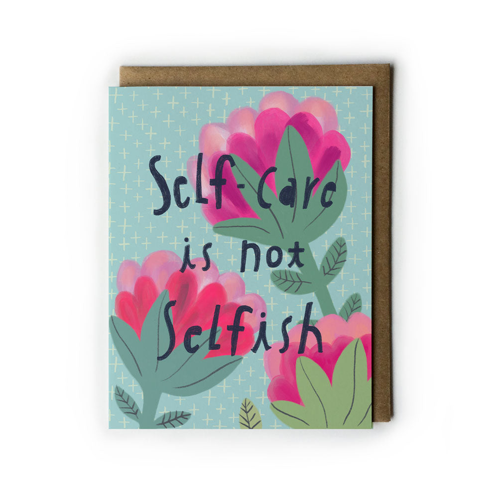 Greeting card with pink floral design on light blue background, featuring handwritten text "Self-care is not Selfish" and paired with kraft paper envelope