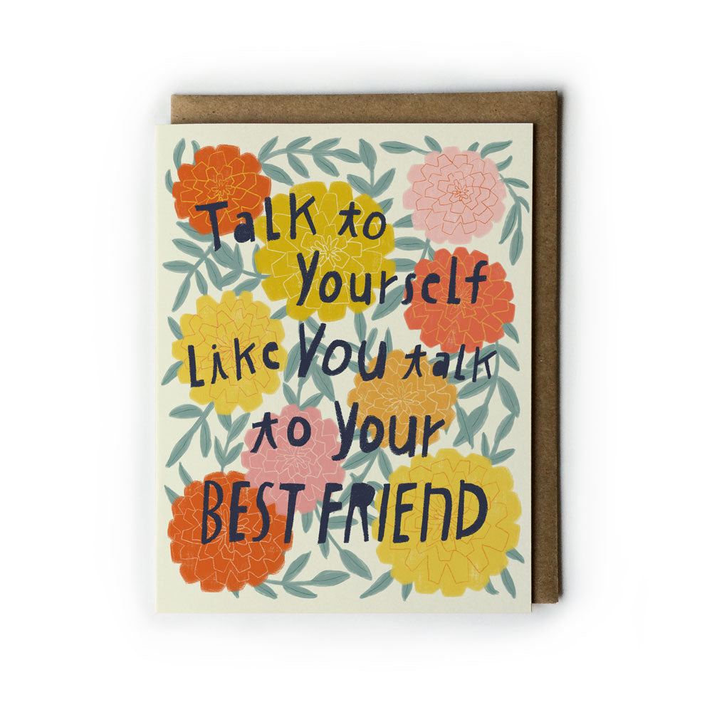 Colorful greeting card with floral design featuring handwritten text "Talk to yourself like you talk to your best friend" surrounded by orange, yellow, and pink flowers with green leaves on white background, paired with kraft paper envelope