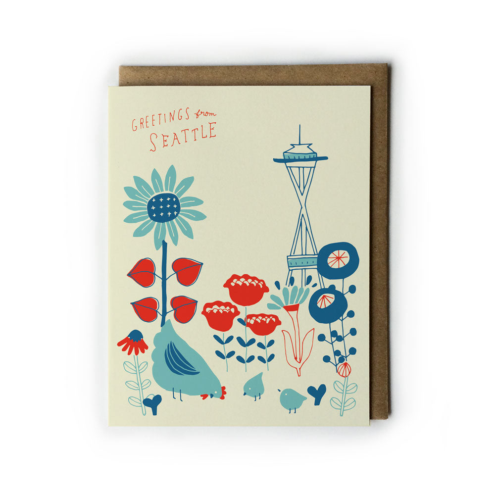 Vintage-style greeting card featuring colorful illustrations of flowers, a chicken family, and Seattle's Space Needle against a cream background. Text reads "Greetings from Seattle" in whimsical handwriting. Card displayed with brown envelope.