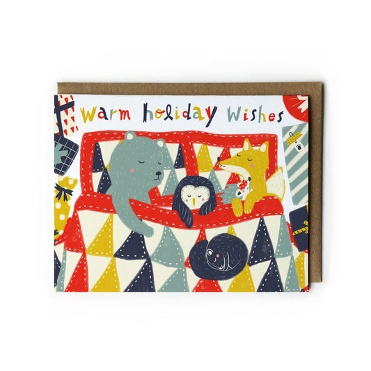 Colorful holiday greeting card featuring cute cartoon animals on a geometric patterned background, with "Warm holiday wishes" text, paired with kraft paper envelope