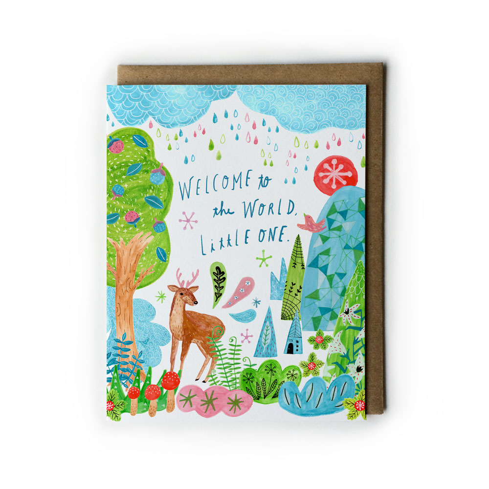 Colorful baby greeting card featuring whimsical forest scene with deer, trees, flowers, and handwritten text 'Welcome to the World, Little One' on blue sky background, paired with kraft paper envelope