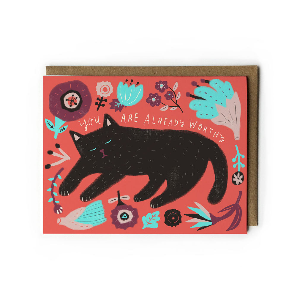 Illustrated greeting card featuring a black cat surrounded by colorful floral designs on a vibrant coral background, with the message "You are already worthy" written above the cat in white lettering