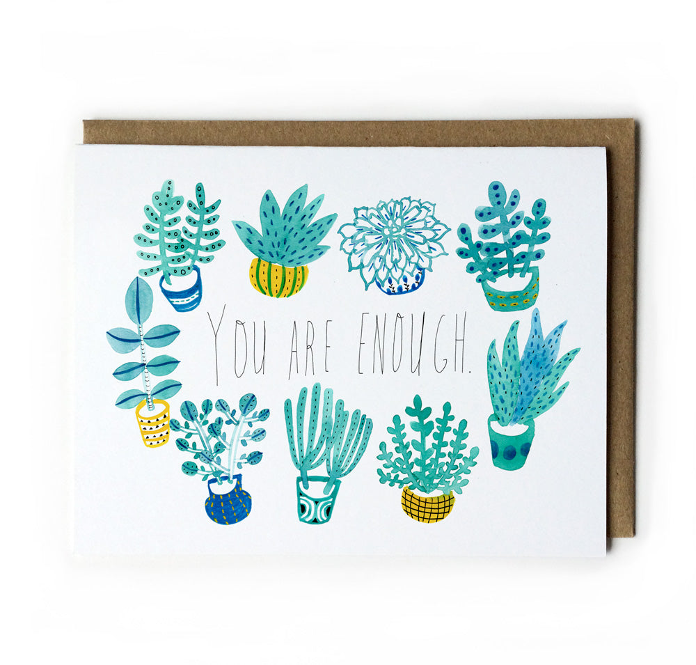 Greeting card with handwritten text "You are enough" surrounded by colorful illustrations of potted succulents and plants in teal, blue, and yellow, paired with a kraft paper envelope