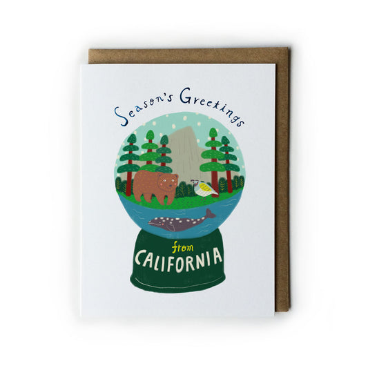 Holiday greeting card featuring a California-themed snow globe with trees, bear, fish, and iconic landmarks, accompanied by a kraft paper envelope. The globe reads "Season's Greetings from California" in festive typography.