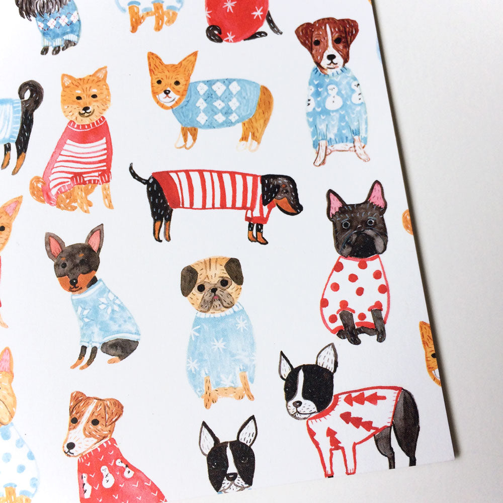 Cute watercolor illustration of various dog breeds and cats wearing colorful festive sweaters and outfits on a white greeting card, perfect for holiday season