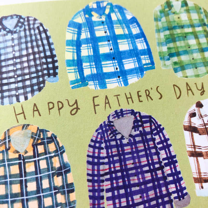Father's Day card featuring colorful illustrated plaid flannel shirts arranged around text saying "HAPPY FATHER'S DAY" on a light green background
