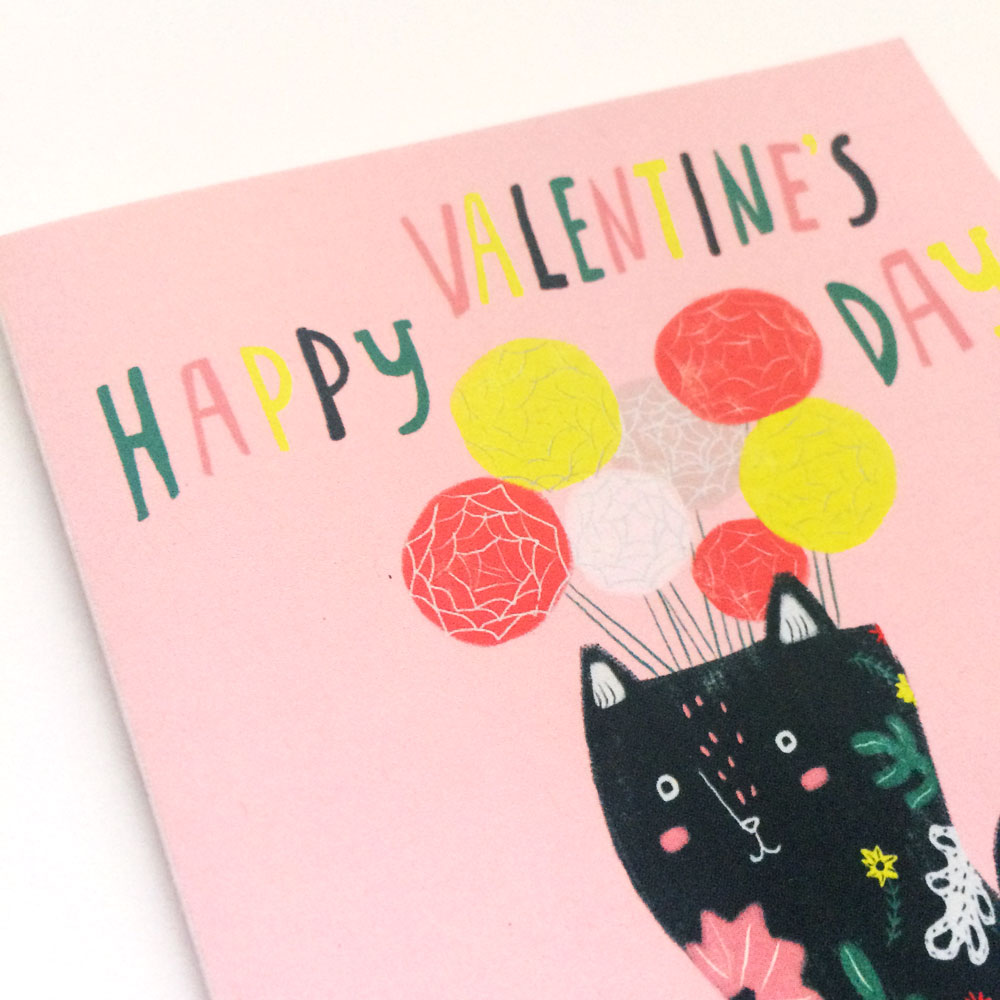 Whimsical Valentine's Day card featuring a black cat-shaped vase holding colorful balloon-like flowers, with 'Happy Valentine's Day' text in vibrant letters on a pink background