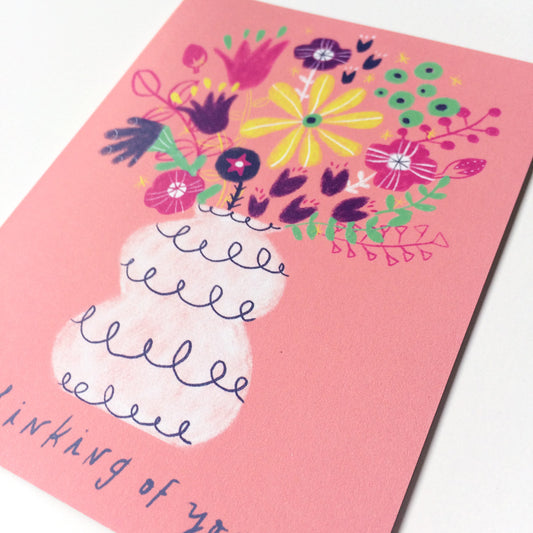 Colorful hand-drawn floral bouquet in white vase on pink greeting card with partial "Thinking of you" text visible