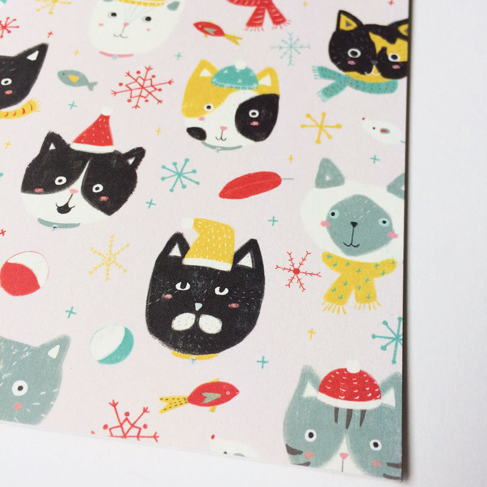 Whimsical holiday greeting card design featuring colorful cat faces, snowflakes, and festive elements on a white background. Cute cartoon-style cats in various expressions and winter accessories create a playful, cat-lover themed winter scene.