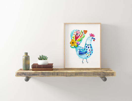Colorful watercolor rooster art print in wooden frame displayed on rustic shelf with decorative items, showcasing vibrant blue body and multicolored floral tail feathers