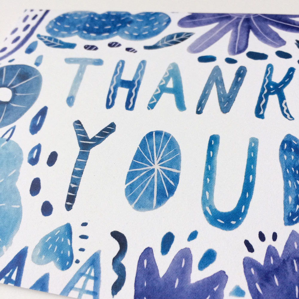 Handmade watercolor thank you card featuring blue and purple floral designs with "THANK YOU" text in stylized lettering, printed on white recycled card stock