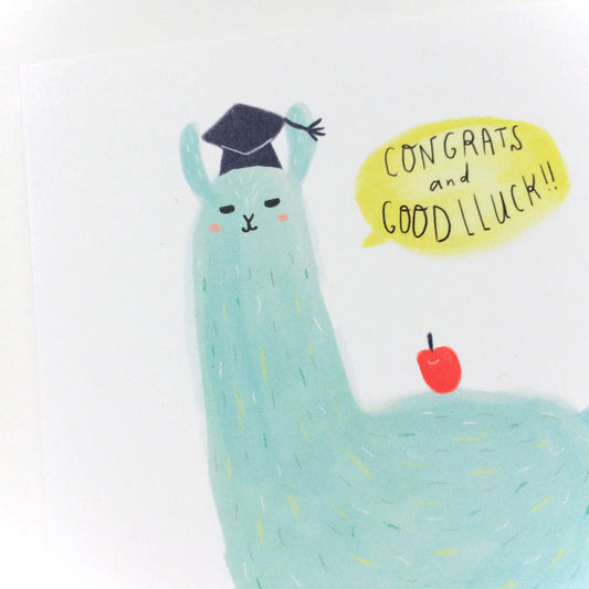 Cute cartoon llama wearing graduation cap with speech bubble saying "Congrats and Good Lluck" and red apple, on white background. Colorful illustration for graduation card.