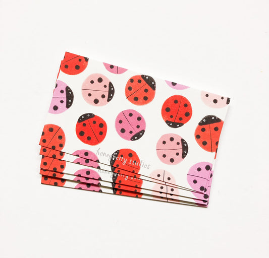 Set of small rectangular cards featuring colorful ladybug pattern in red and pink on white background, stacked together with a white band, ideal for mini greetings or gift tags