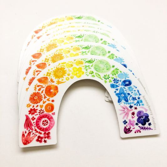 Colorful rainbow arch sticker composed of diverse flower illustrations, arranged in a spectrum from red to purple, creating a cheerful and vibrant design perfect for Pride celebrations or as a decorative accent.