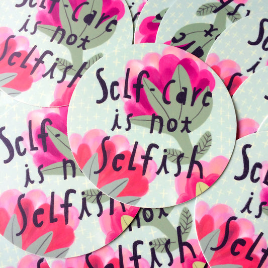 Colorful vinyl stickers with pink hearts and green leaves, featuring the message "Self-care is not selfish" in handwritten text, arranged in a repeating pattern on a light background.