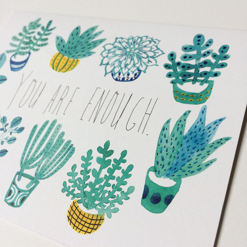 Watercolor greeting card with "You are enough" message surrounded by whimsical illustrations of potted plants, including succulents, pineapple, and floral designs in shades of green, blue, and yellow
