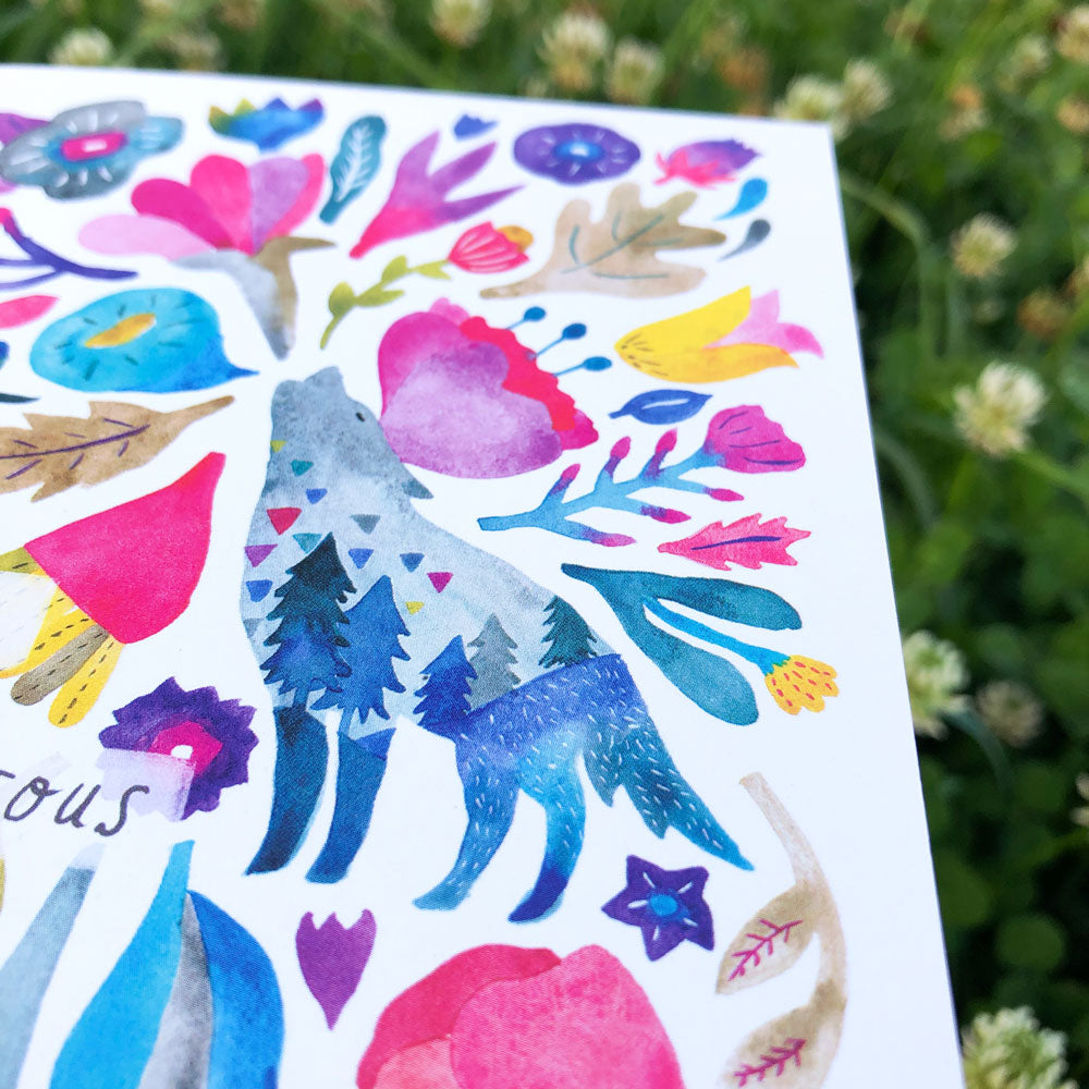 Colorful watercolor greeting card featuring a vibrant coyote silhouette surrounded by floral and nature-inspired elements, including mountains, trees, and various flowers in shades of blue, pink, purple, and yellow on a white background