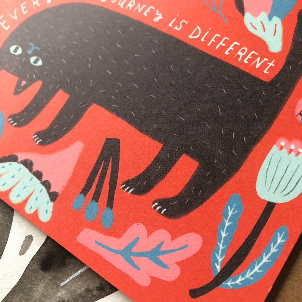 Colorful greeting card featuring a black cat on red background with text "Everyone's journey is different" and floral elements, emphasizing uniqueness and encouragement