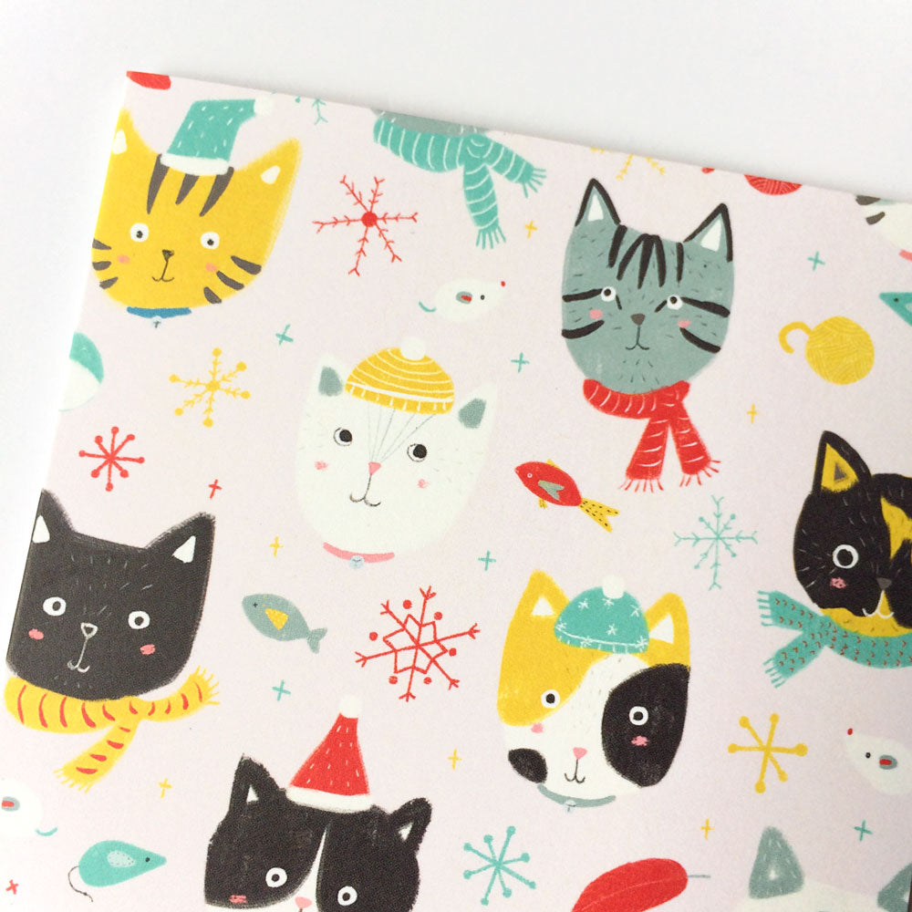 Festive greeting card featuring cute cartoon cat faces with winter accessories, snowflakes, and holiday motifs on a white background, perfect for cat lovers and holiday season