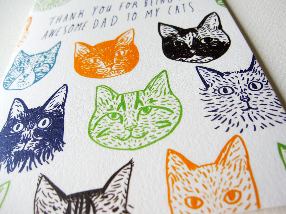 Colorful hand-drawn cat faces on a Father's Day card with text "Thank you for being awesome dad to my cats" in various colors including blue, orange, green, and black on white paper