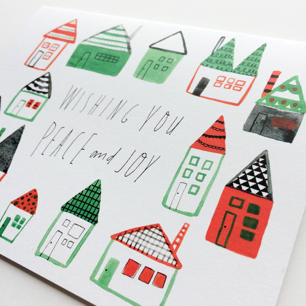 Whimsical watercolor holiday card featuring colorful folk houses with handwritten message "Wishing You Peace and Joy" in green and red design, perfect for non-traditional Christmas greetings