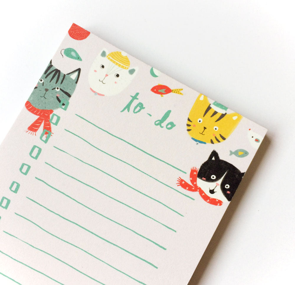 Winter Kitties To-Do List notepad featuring cute cartoon cats in colorful winter accessories, with lined paper for writing tasks. Playful design includes fish and yarn ball motifs, perfect for cat lovers and holiday organization.