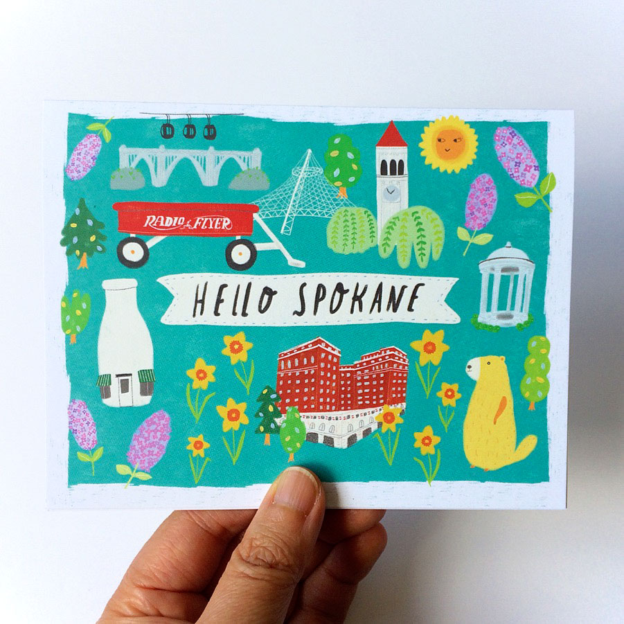 Colorful illustrated greeting card featuring Spokane landmarks and symbols including Monroe Bridge, Big Red Wagon, Clocktower, Davenport Hotel, Milk Bottle, and marmot on turquoise background with Hello Spokane text banner
