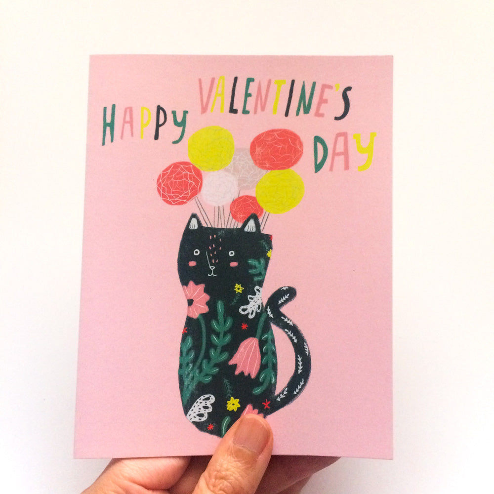 Whimsical Valentine's Day card featuring a cat-shaped vase with floral pattern, holding colorful balloons, on a pink background with hand-lettered 'Happy Valentine's Day' message