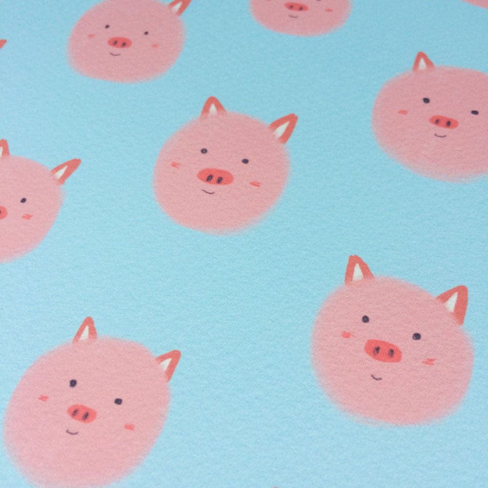 Cute pink pig faces pattern on light blue background, giclee art print titled "Little Piggies". Adorable round piglet heads with pointy ears and snouts, smiling expressions. Playful and whimsical design for home decor or children's room.