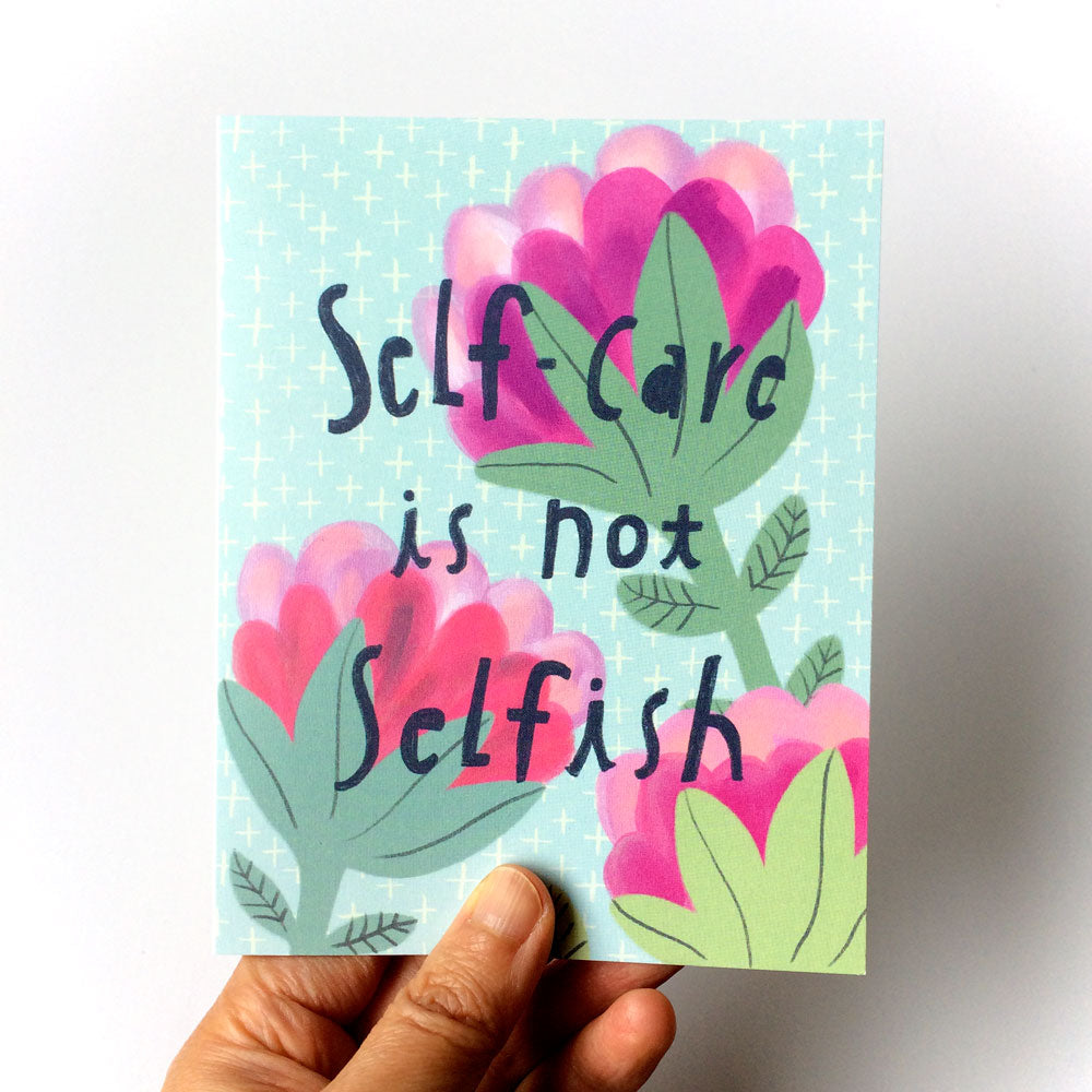 Whimsical greeting card with colorful flowers and text "Self-care is not selfish" on light blue background, held by a hand, promoting self-care and personal wellness