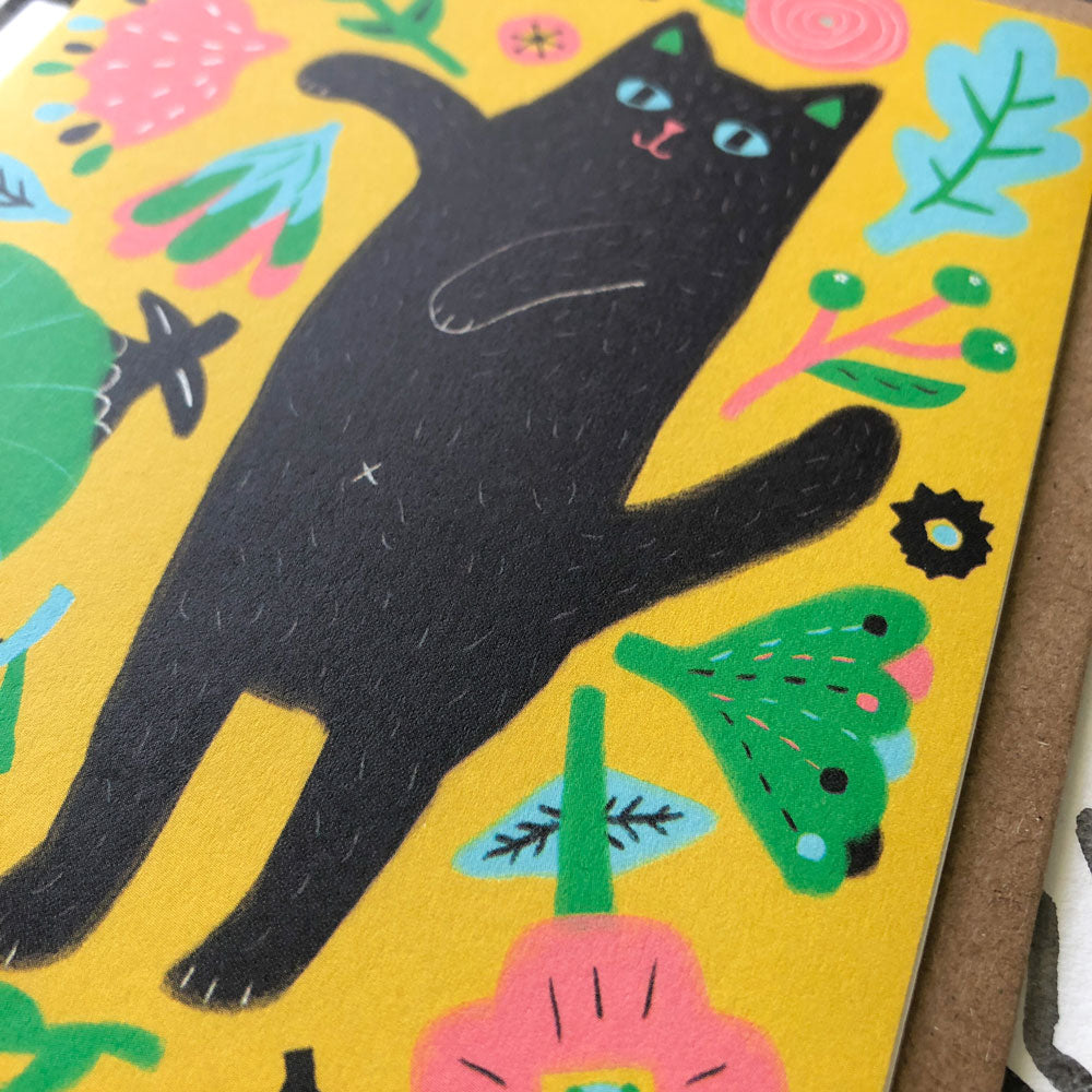 Colorful greeting card featuring a playful black cat surrounded by vibrant floral and leaf designs on a bright yellow background, perfect for expressing gratitude