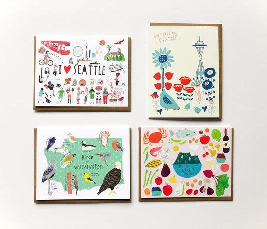 Set of four illustrated greeting cards featuring Seattle and Pacific Northwest themes: city landmarks, Space Needle, local birds, and regional foods. Each card has colorful, whimsical designs on white backgrounds with kraft paper envelopes.