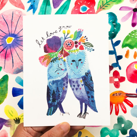 Colorful watercolor greeting card featuring two whimsical blue owls with floral designs, surrounded by vibrant abstract flowers and leaves. The owls are cuddling, with "Let love grow" text above them, symbolizing love and growth.