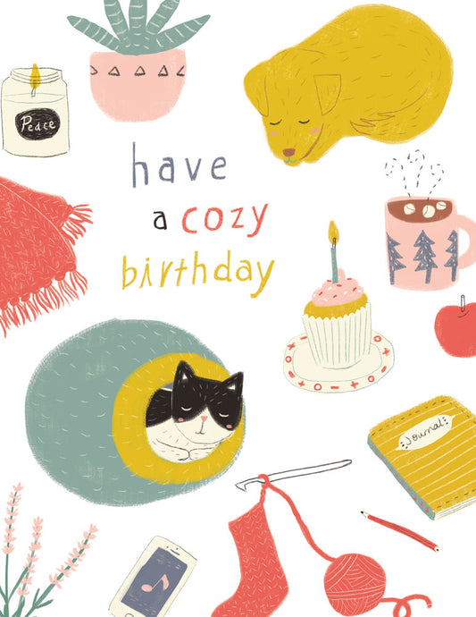 Cozy birthday card illustration featuring peaceful elements like a sleeping dog, cat on a cushion, cupcake, candle, knitting, houseplant, and warm beverages, with "have a cozy birthday" text in pastel colors
